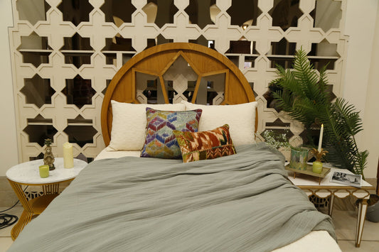 Sage crinkle quilt over ivory bedcover with jewel-toned ikat cushion covers