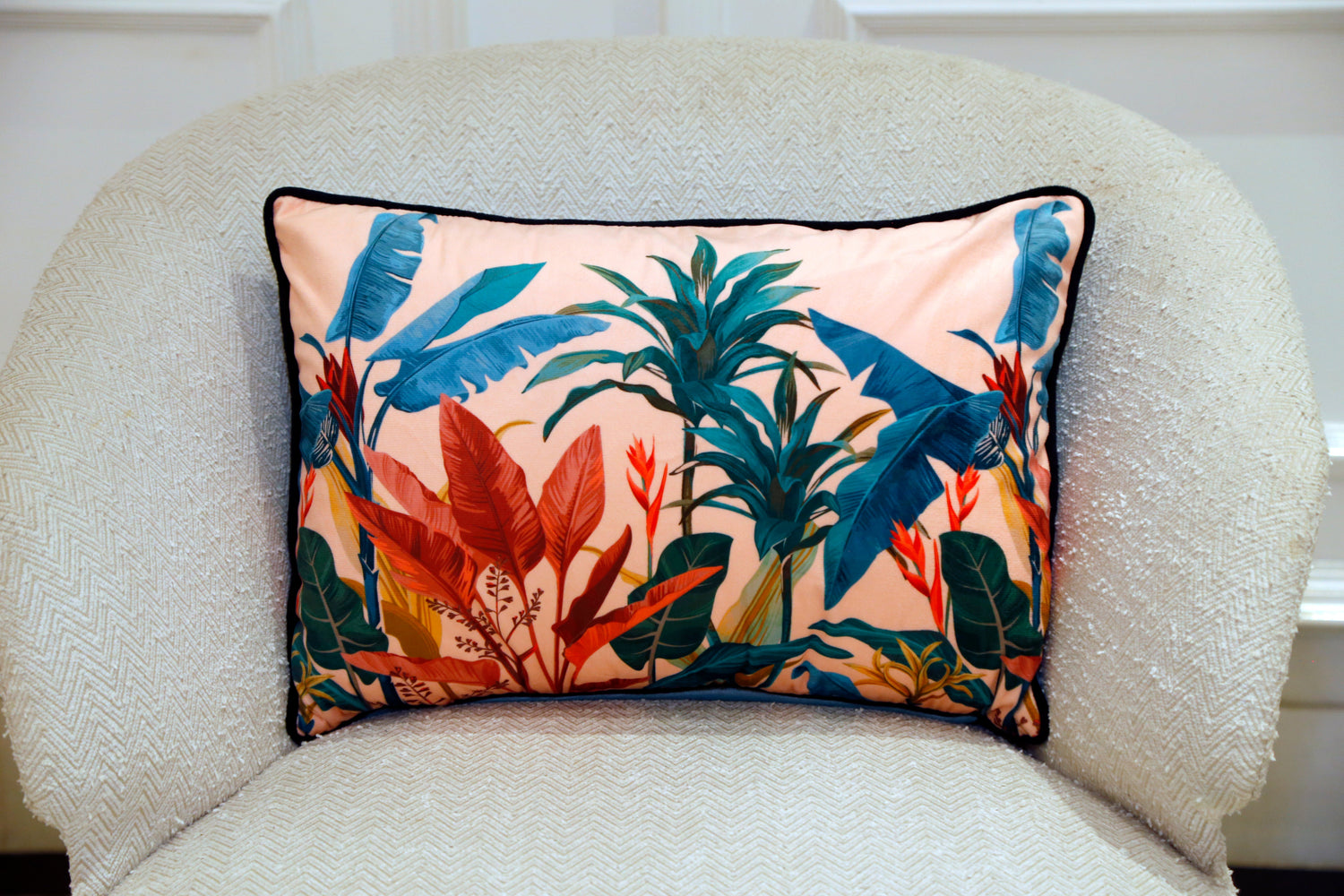 Tropical print velvet cushion on a boucle chair