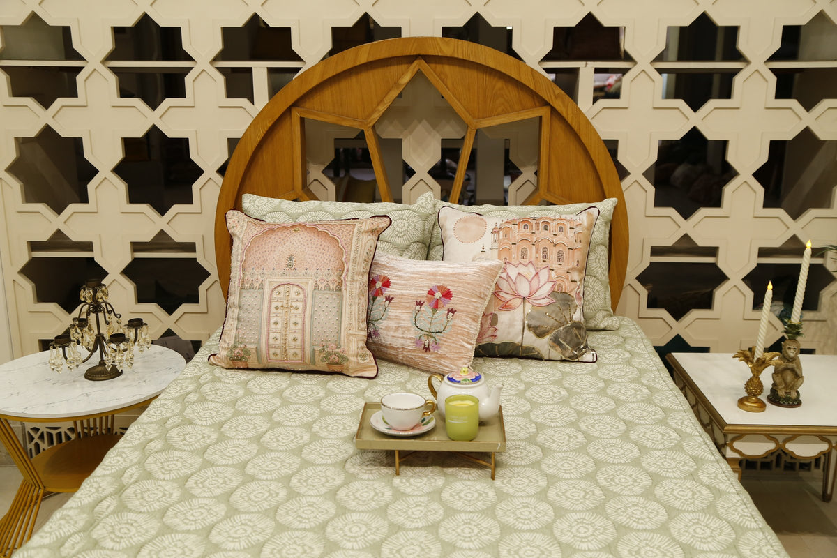 Sage green block printed bedcover set styled with blush jharokha and lotus cushion covers