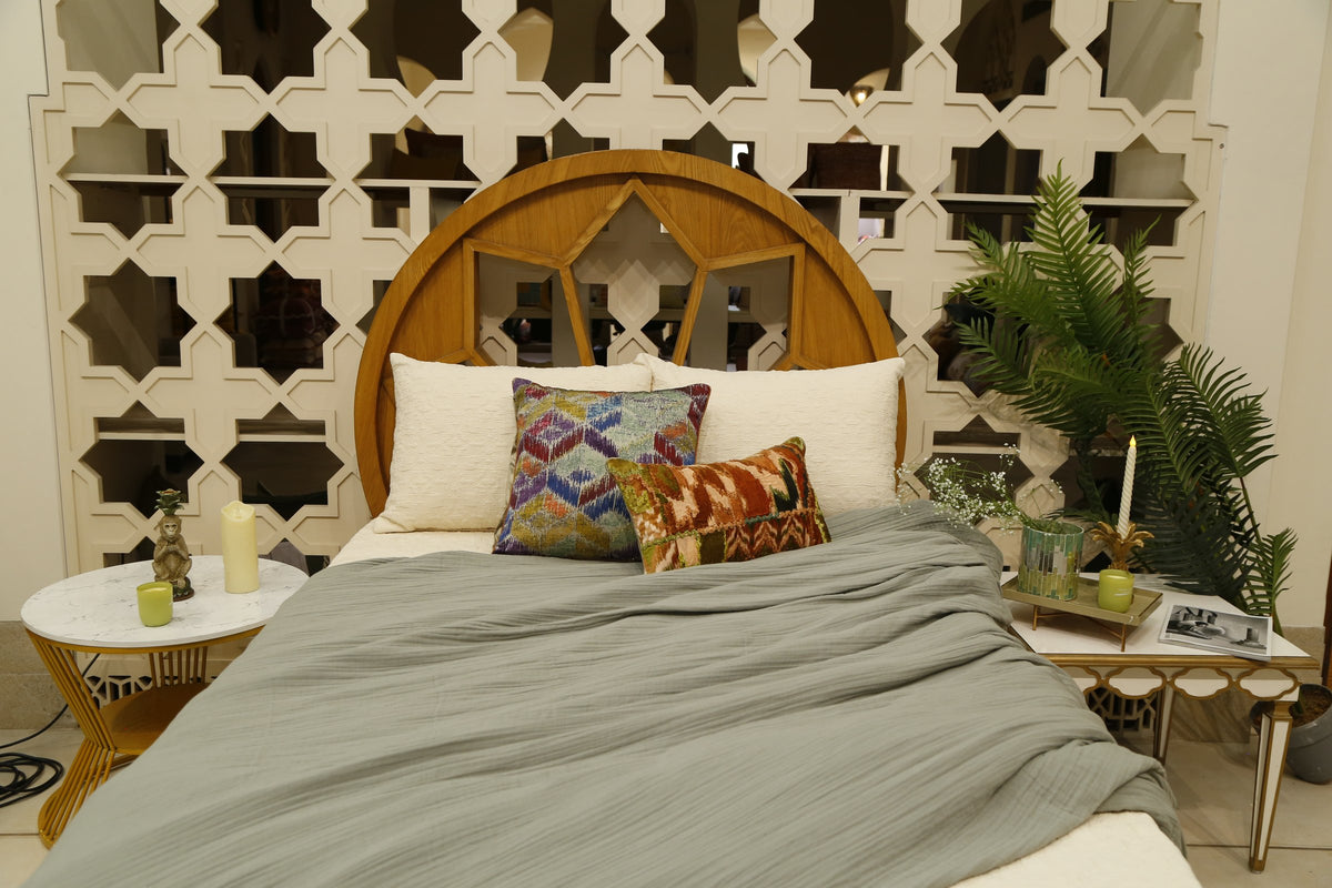 Sage crinkle quilt over ivory bedcover with jewel-toned ikat cushion covers