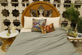 Sage crinkle quilt over ivory bedcover with jewel-toned ikat cushion covers