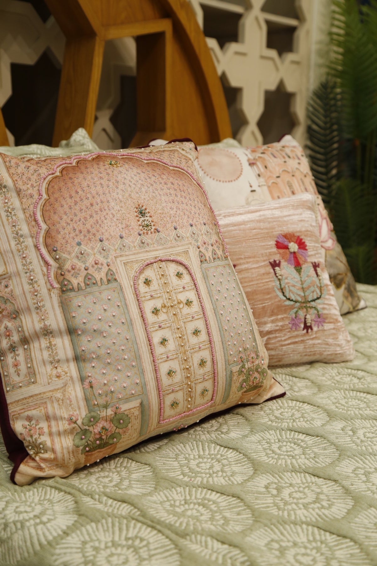 Blush pink jharokha cushion cover with lotus cushion, styled on a sage bedcover