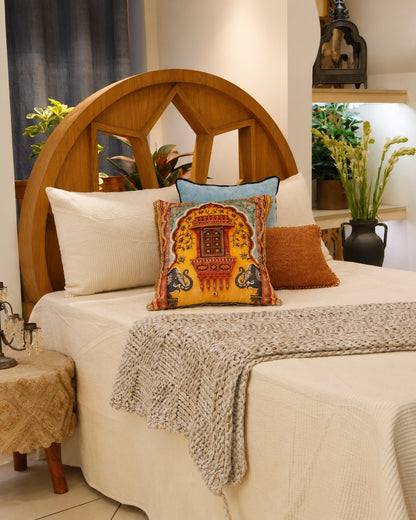 Royal Jharokha cushion styled on a made bed with a knitted throw