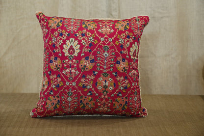 Ruby red floral silk cushion cover, angled view on a woven bench