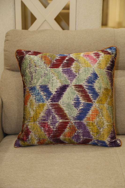 Multicoloured harlequin diamond ikat printed silk cushion cover styled on a linen armchair