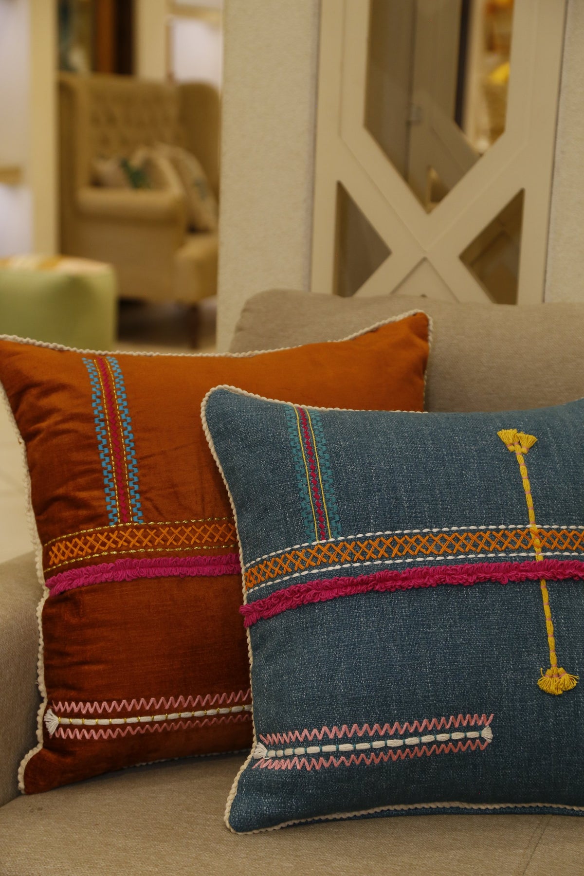 Teal hand-embroidered cushion cover styled beside the rust colourway