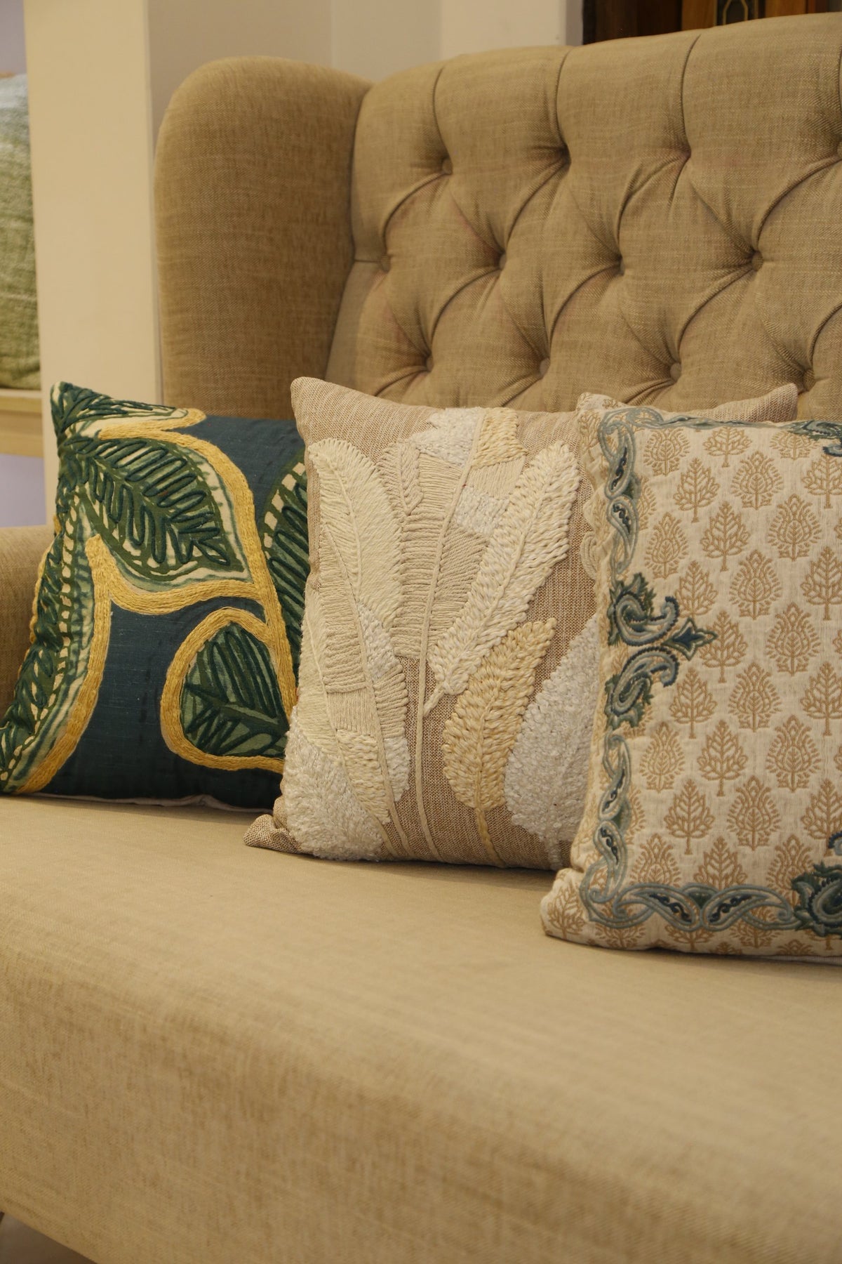 Forest green leaf embroidered cushion cover styled with the natural and sand colourways
